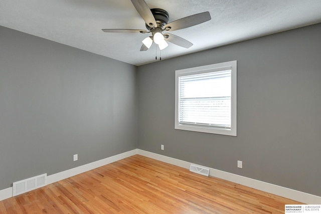 unfurnished room featuring light wood-type flooring, baseboards, visible vents, and a ceiling fan