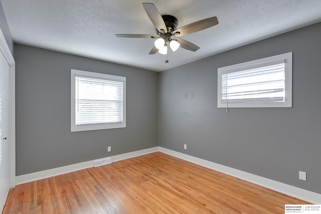 unfurnished room featuring light wood-style floors, visible vents, ceiling fan, and baseboards