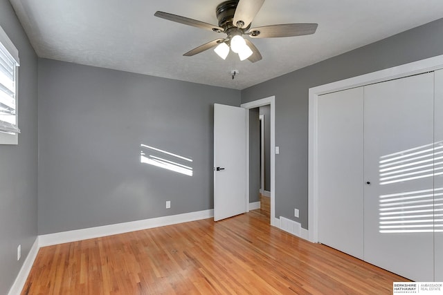 unfurnished bedroom with light wood-style floors, a ceiling fan, baseboards, and a closet