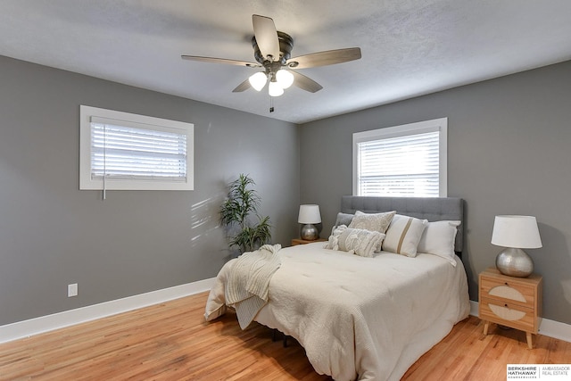 bedroom featuring ceiling fan, light wood-style flooring, and baseboards