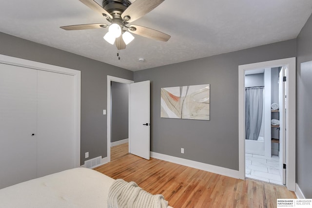 bedroom with a closet, visible vents, baseboards, and wood finished floors