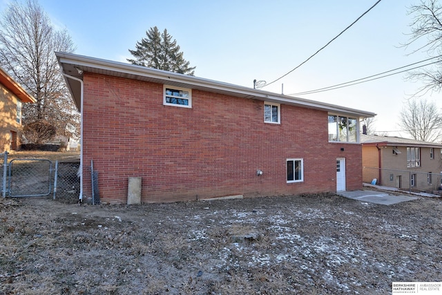 view of side of property featuring brick siding, fence, and a gate