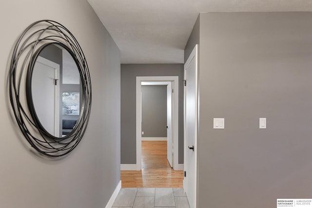 hall with light wood-style floors and baseboards