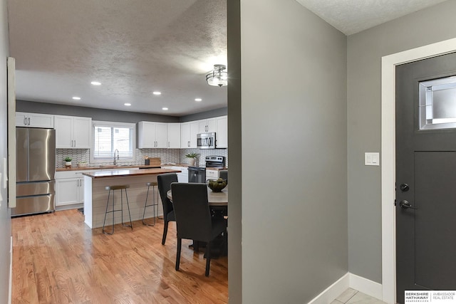 kitchen with tasteful backsplash, white cabinetry, and stainless steel appliances