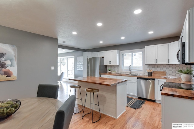 kitchen featuring stainless steel appliances, butcher block counters, a sink, and light wood-style floors