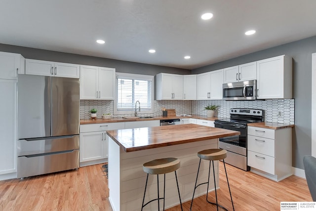 kitchen featuring appliances with stainless steel finishes, white cabinets, butcher block countertops, and a sink