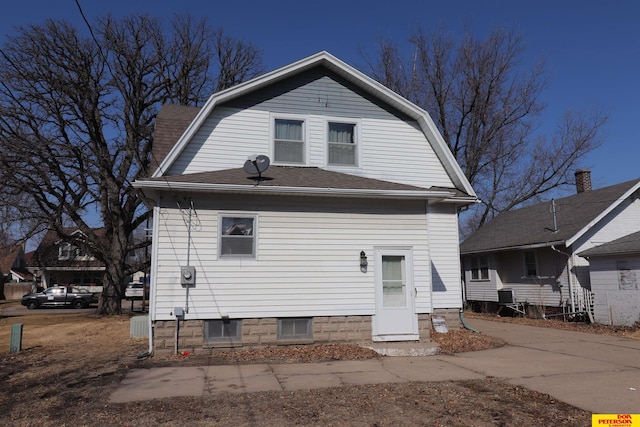 rear view of house with a gambrel roof and roof with shingles