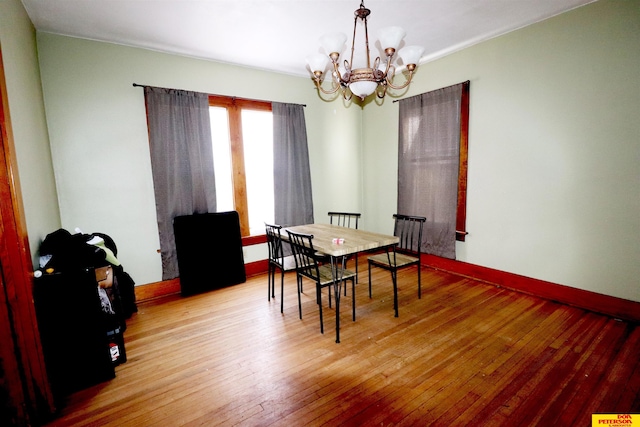 dining space with baseboards, a notable chandelier, and hardwood / wood-style floors