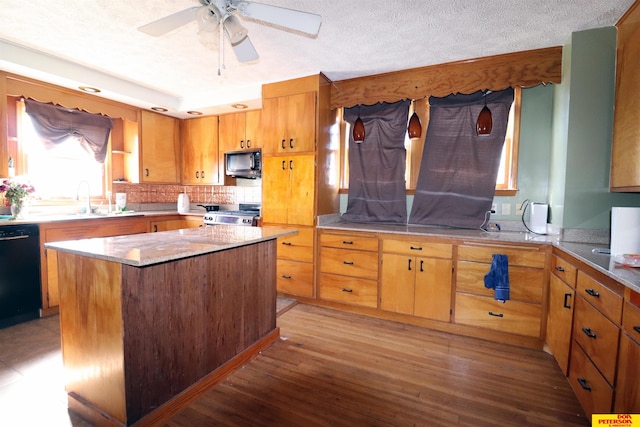 kitchen featuring black appliances, a sink, a kitchen island, a textured ceiling, and light wood-style floors