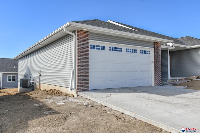 view of home's exterior featuring a garage, driveway, brick siding, and cooling unit