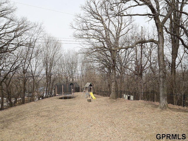 view of yard with a trampoline, a playground, and fence