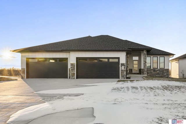 prairie-style house with a garage, stone siding, and a shingled roof