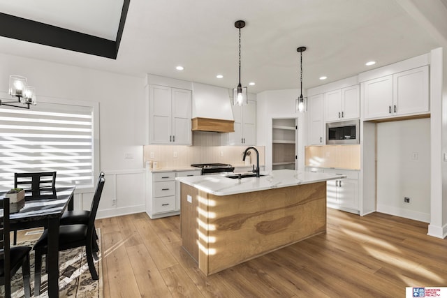 kitchen featuring premium range hood, white cabinetry, stainless steel appliances, and a sink