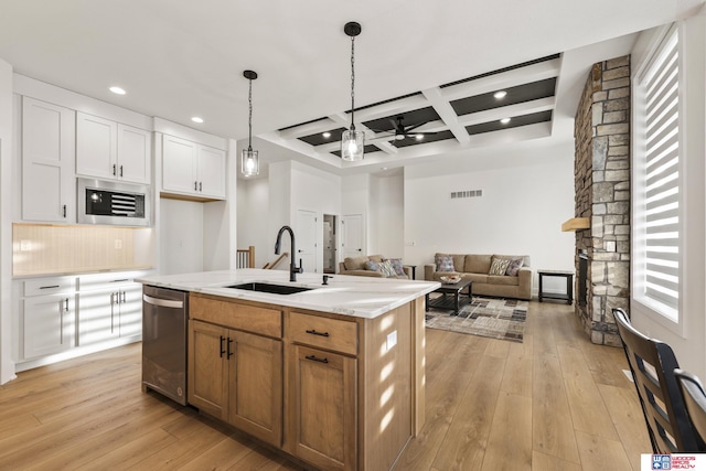 kitchen with appliances with stainless steel finishes, a fireplace, a sink, and light wood-style flooring