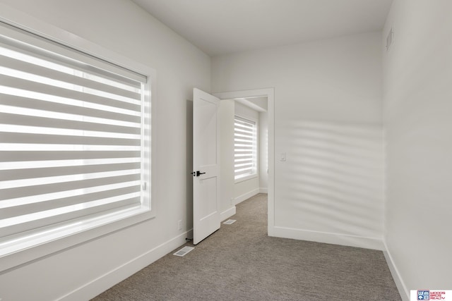 carpeted spare room featuring visible vents and baseboards