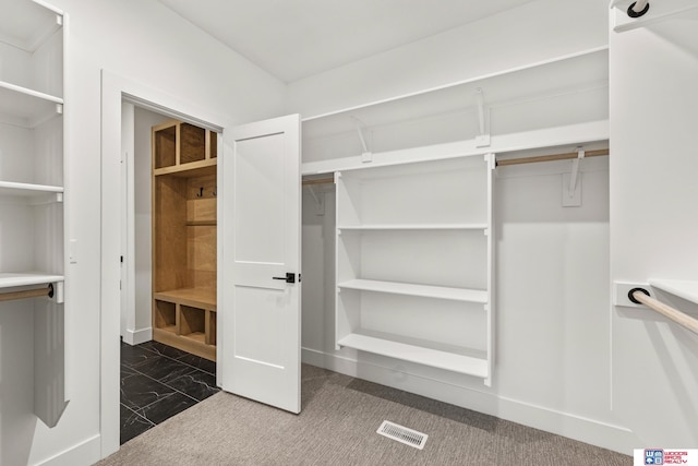 spacious closet with dark carpet and visible vents