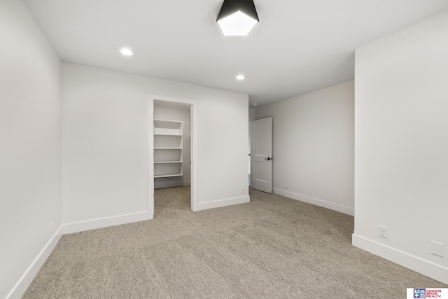 unfurnished bedroom featuring baseboards, carpet, a walk in closet, a closet, and recessed lighting