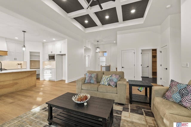 living area with light wood-style flooring, recessed lighting, a high ceiling, coffered ceiling, and beamed ceiling