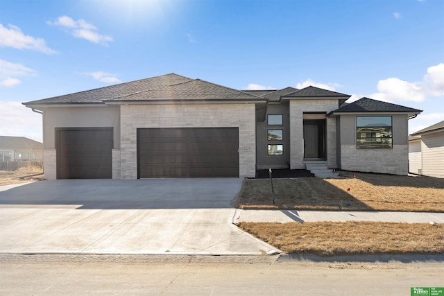 prairie-style house featuring a garage, concrete driveway, a shingled roof, and entry steps