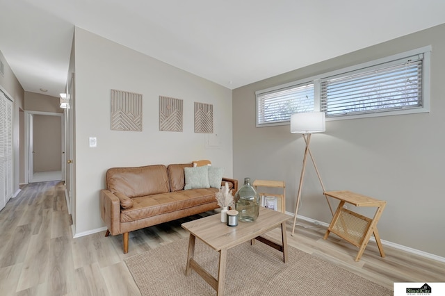 living area featuring lofted ceiling, baseboards, visible vents, and light wood finished floors