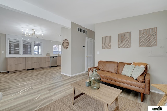 living area with a chandelier, baseboards, visible vents, and light wood finished floors