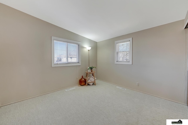 carpeted empty room with vaulted ceiling and visible vents