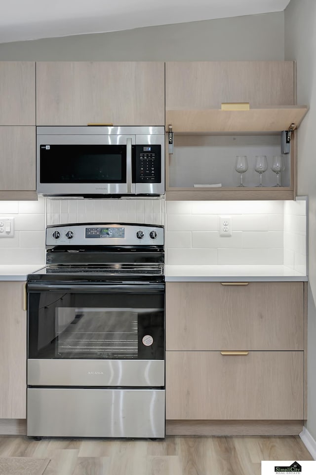 kitchen with stainless steel appliances, light countertops, light brown cabinets, and backsplash