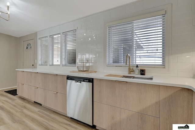 kitchen featuring dishwasher, backsplash, light wood-style floors, light brown cabinets, and a sink