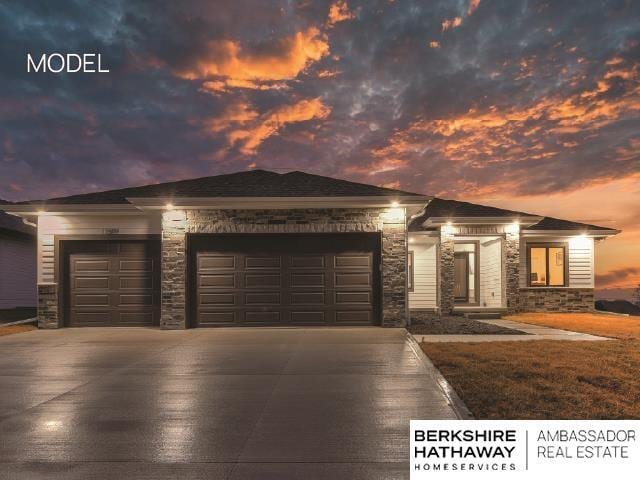 prairie-style home with a garage, stone siding, and driveway