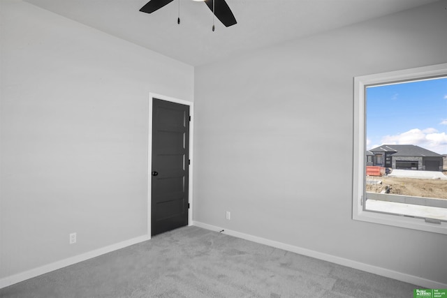 carpeted empty room with ceiling fan and baseboards