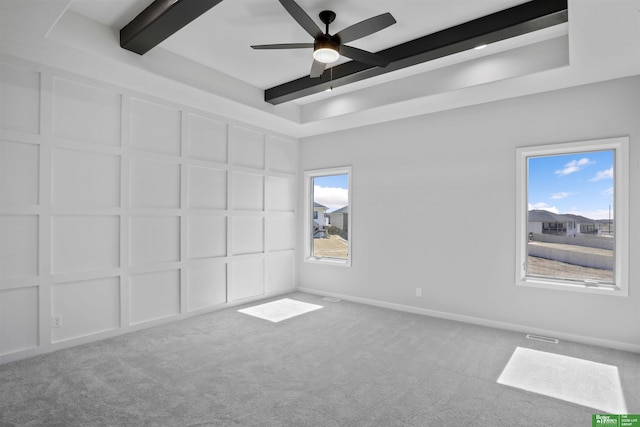 unfurnished bedroom with baseboards, carpet floors, beamed ceiling, and a decorative wall