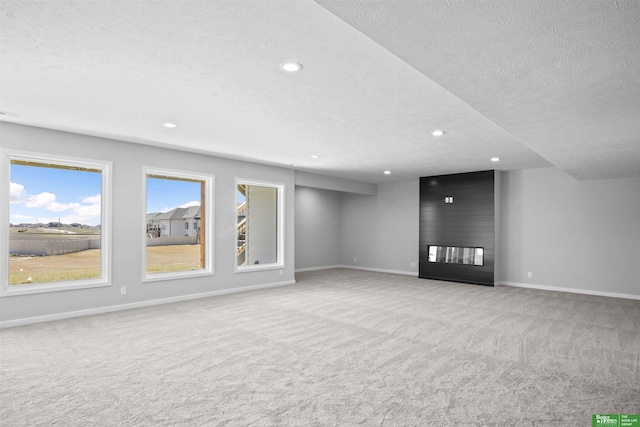 unfurnished living room featuring carpet, a textured ceiling, and baseboards