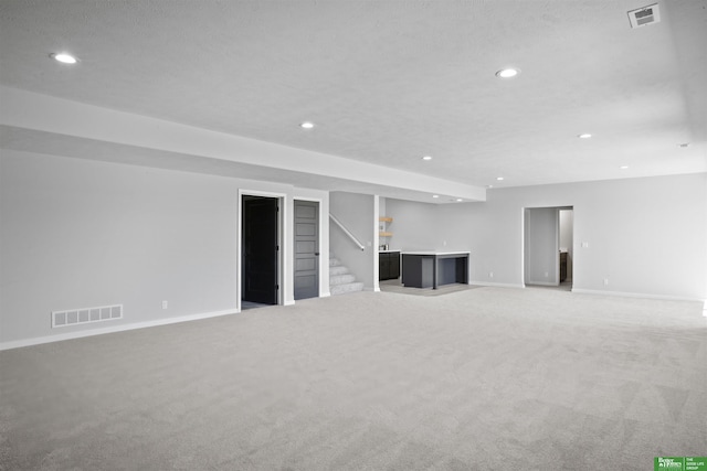 unfurnished living room with light carpet, stairway, visible vents, and recessed lighting