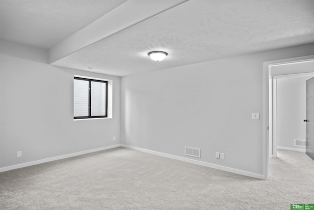 carpeted empty room with visible vents, a textured ceiling, and baseboards