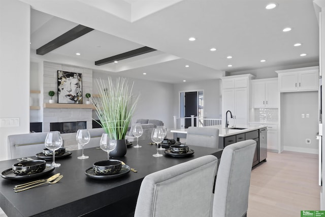 dining area featuring recessed lighting, beam ceiling, a glass covered fireplace, and light wood-style flooring