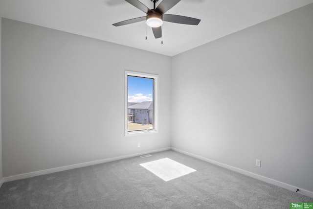 carpeted spare room featuring a ceiling fan and baseboards