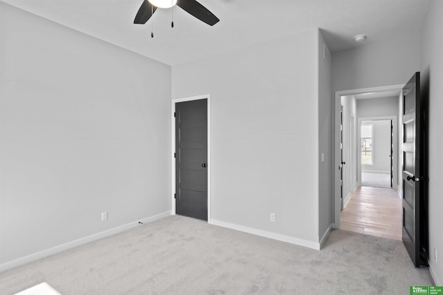 unfurnished bedroom featuring light carpet, baseboards, and a ceiling fan