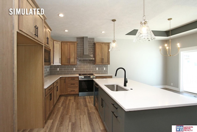 kitchen with a sink, tasteful backsplash, wood finished floors, appliances with stainless steel finishes, and wall chimney exhaust hood