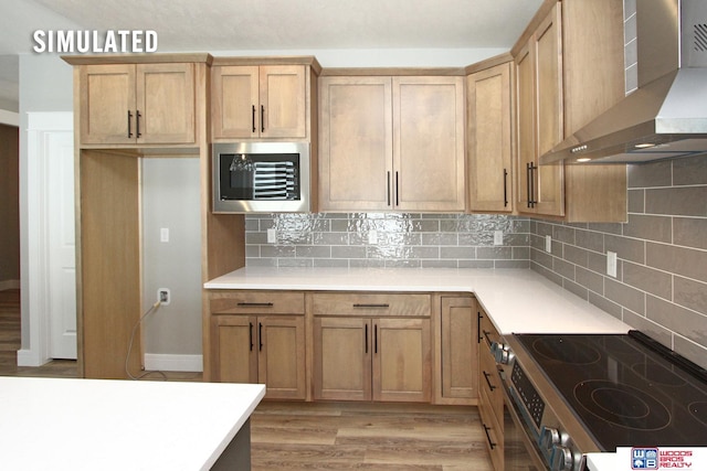 kitchen featuring stainless steel range with electric stovetop, wall chimney range hood, tasteful backsplash, light wood-style floors, and light countertops