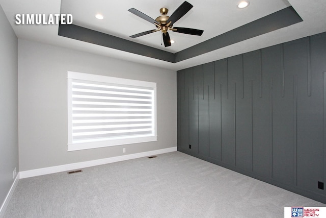 carpeted empty room featuring a tray ceiling, recessed lighting, baseboards, and visible vents