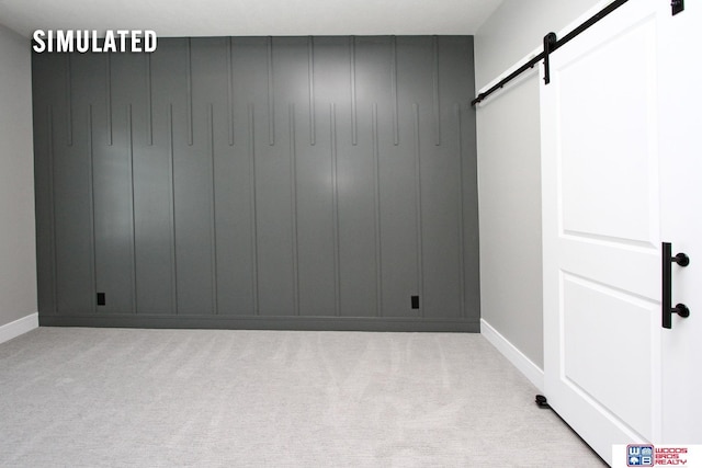 unfurnished room featuring a barn door and carpet