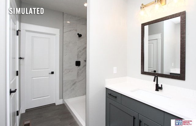 bathroom with vanity, wood finished floors, visible vents, and a tile shower