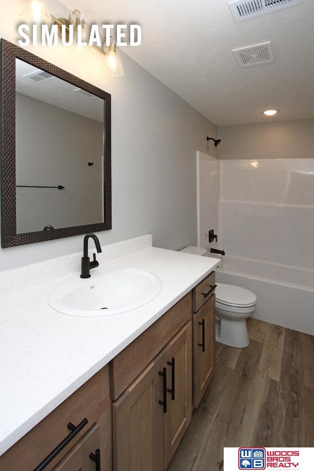 bathroom featuring visible vents, toilet, wood finished floors, bathtub / shower combination, and vanity