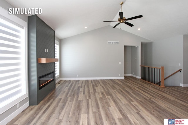 unfurnished living room with baseboards, visible vents, lofted ceiling, a fireplace, and light wood-style floors