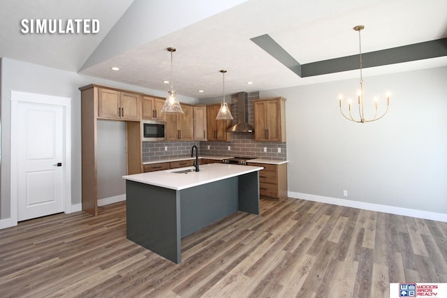 kitchen with light wood finished floors, a sink, stainless steel appliances, wall chimney range hood, and tasteful backsplash