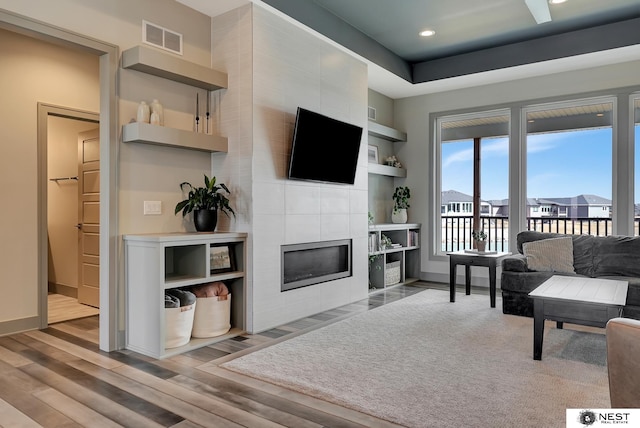 living room with recessed lighting, wood finished floors, visible vents, baseboards, and a tiled fireplace