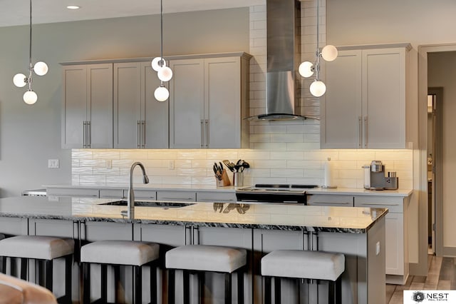 kitchen featuring wall chimney range hood, stainless steel electric range, a sink, and tasteful backsplash