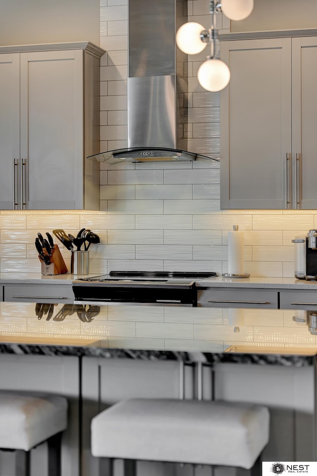 kitchen with wall chimney range hood, backsplash, and stovetop