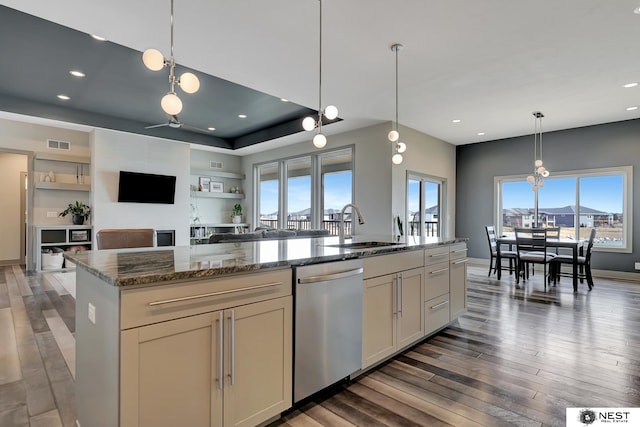 kitchen with stone counters, wood finished floors, a sink, visible vents, and stainless steel dishwasher