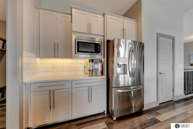 kitchen featuring dark wood-style floors, appliances with stainless steel finishes, light countertops, and decorative backsplash